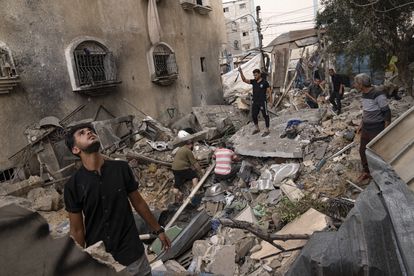 Varios hombres buscan víctimas entre los escombros, tras derruirse un edificio a causa de un ataque israelí, este jueves en Jan Yunis, al sur de la Franja.